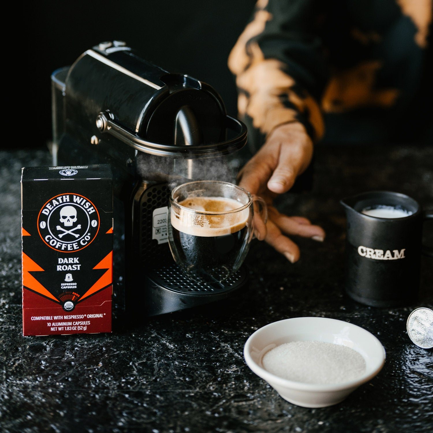 Death Wish Coffee Dark Roast Espresso Capsules beside a fresh espresso
