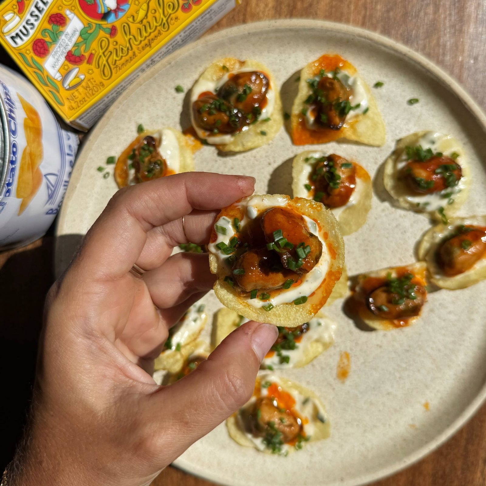 Crackers topped with tinned fish, picked up by hand