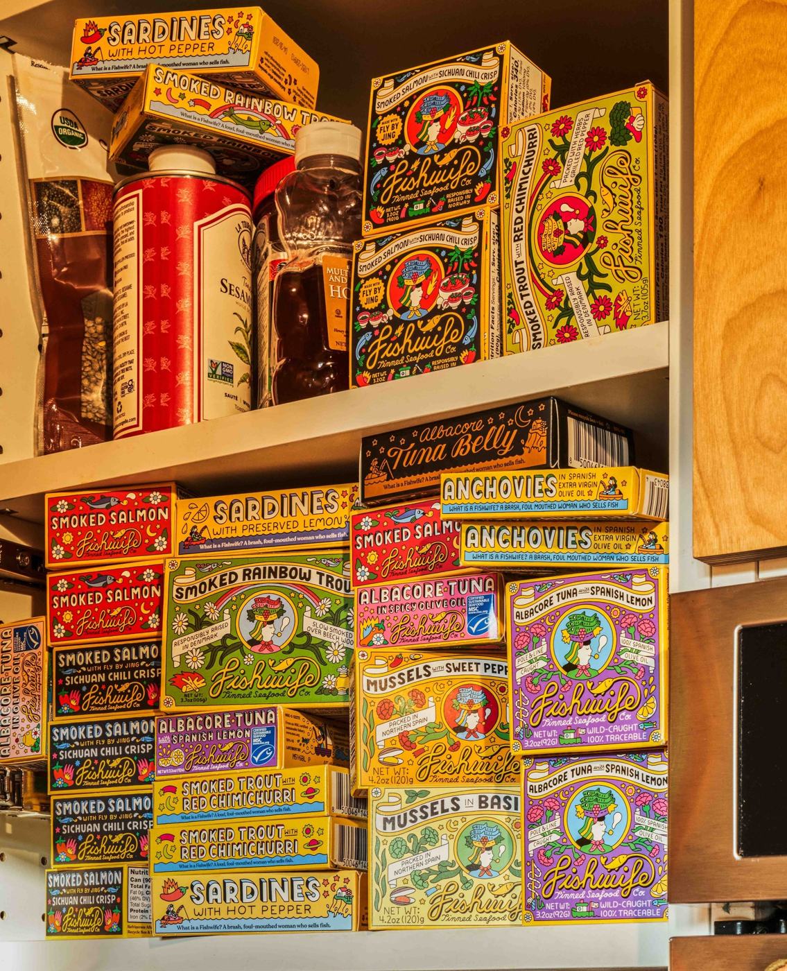 A kitchen shelf stacked with colourful Fishwife tins