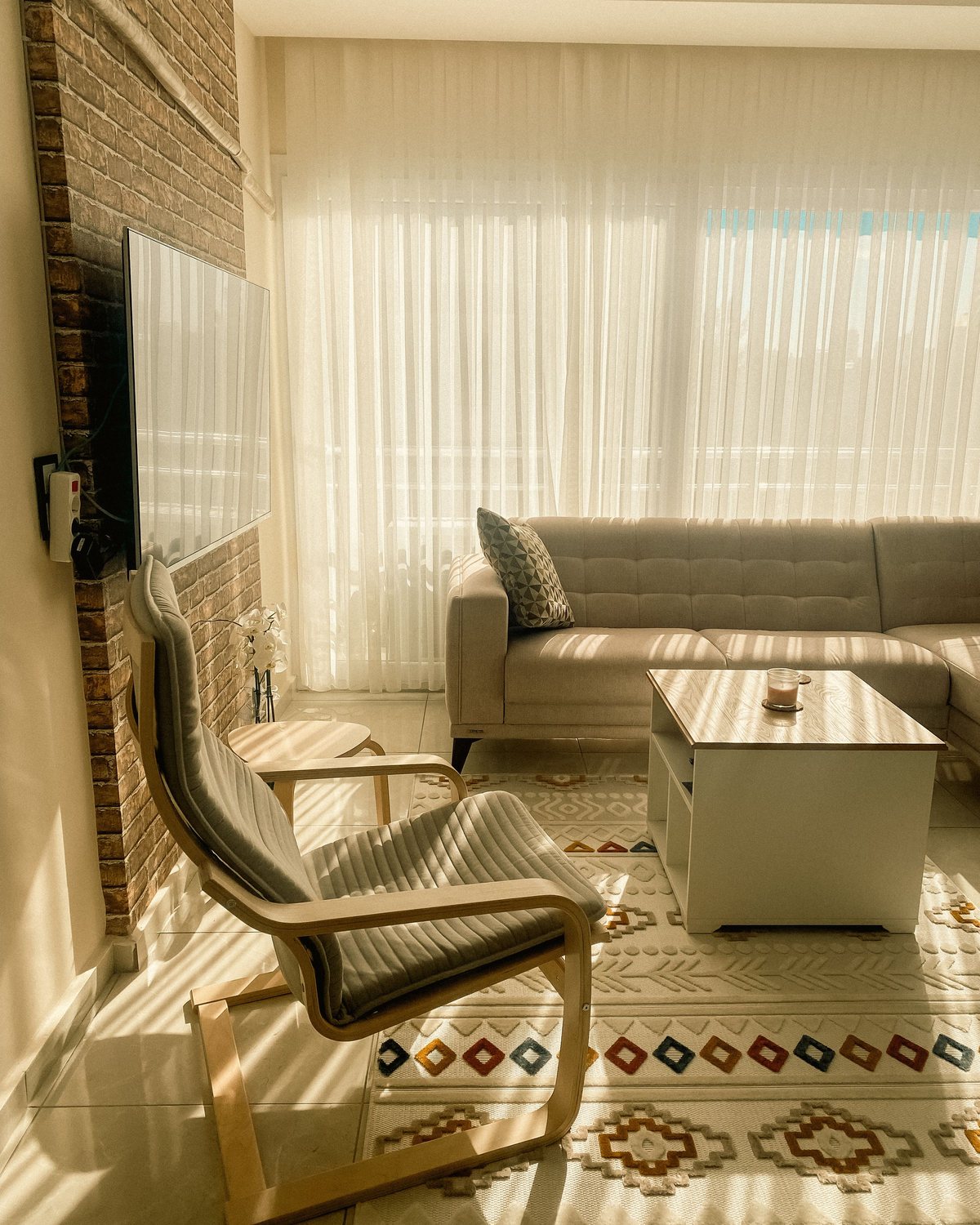 A POÄNG armchair with a grey cushion in a sunlit living room