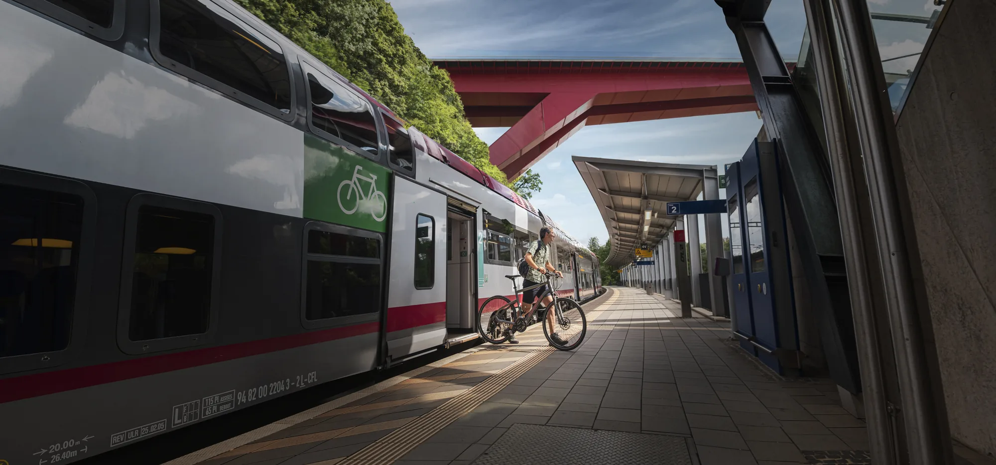 A double-deck train at Pfaffenthal-Kirchberg station under the red bridge